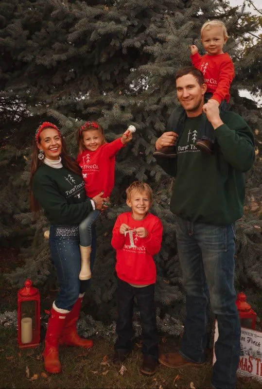 The Turner family standing together by the evergreens